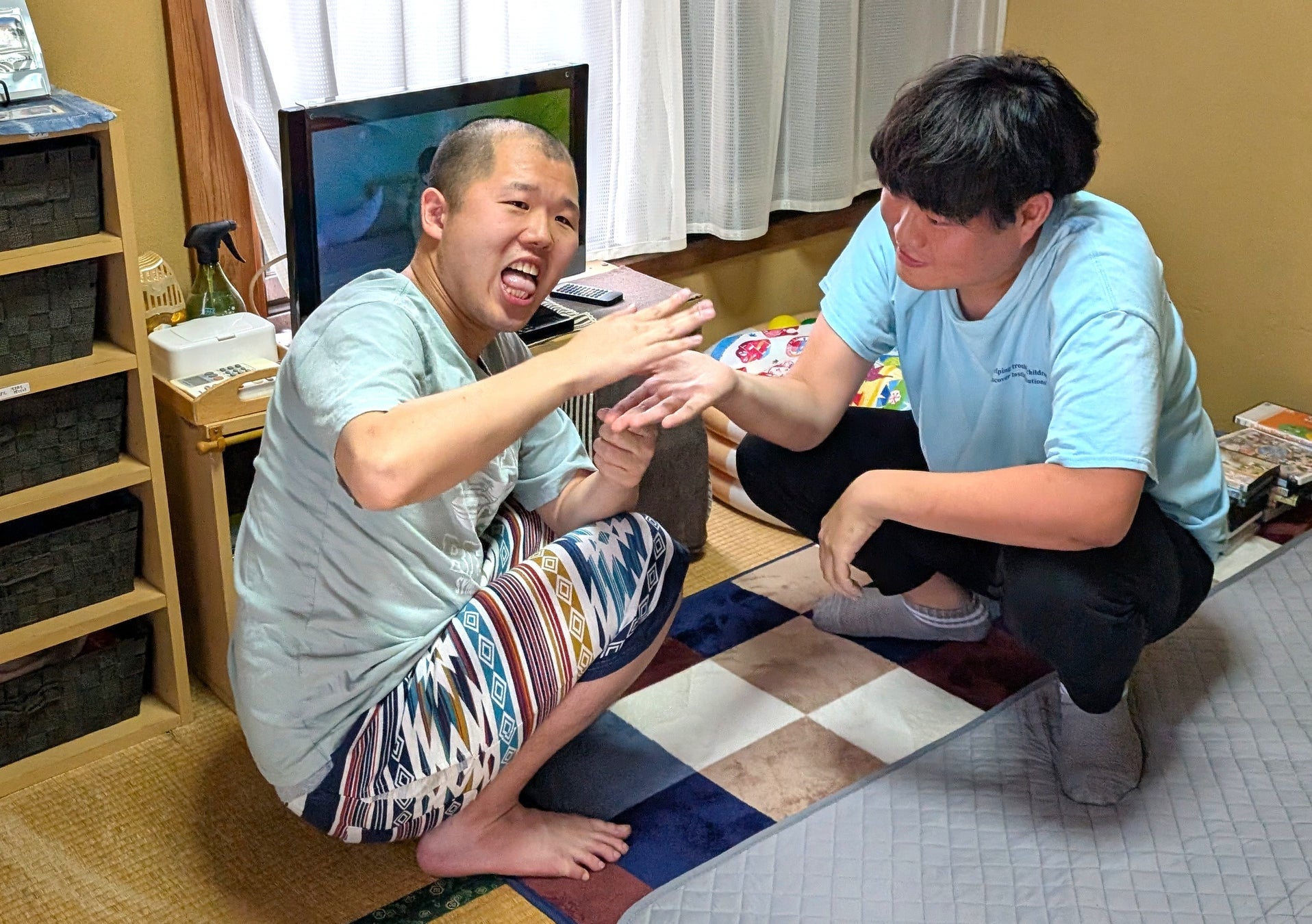A caregiver interacting playfully with a young man in a cozy indoor setting, both appearing engaged and happy.